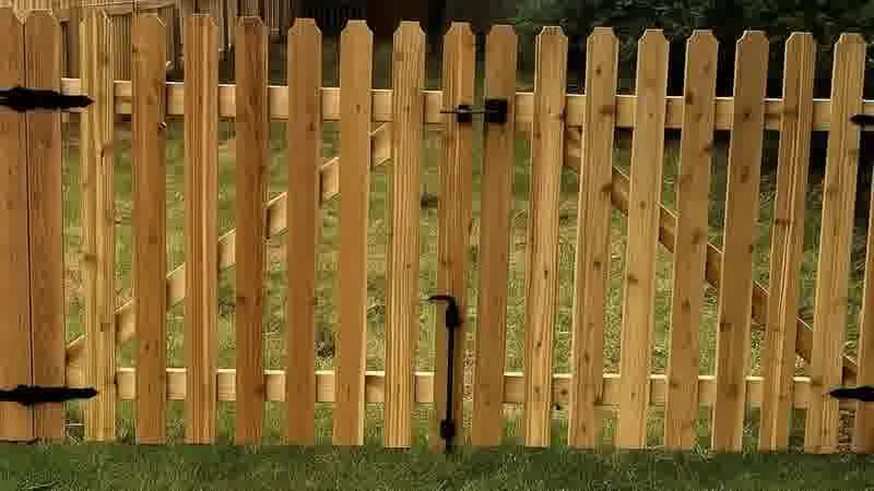 Wood picket gate with black hinges and latch in a residential yard